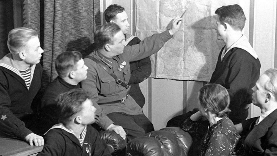 Валерий Чкалов показывает на карте маршрут своего перелета из Москвы в Ванкувер морякам с крейсера «Марат» и рабочим с московской кондитерской фабрики имени Марата