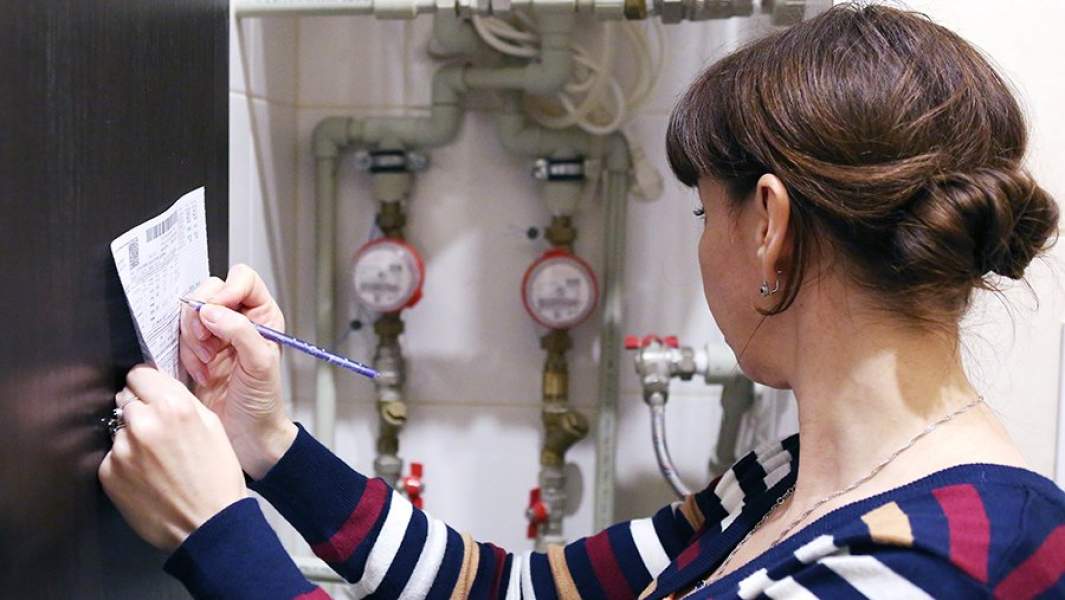 Женщина переписывает показания счетчика учета воды
