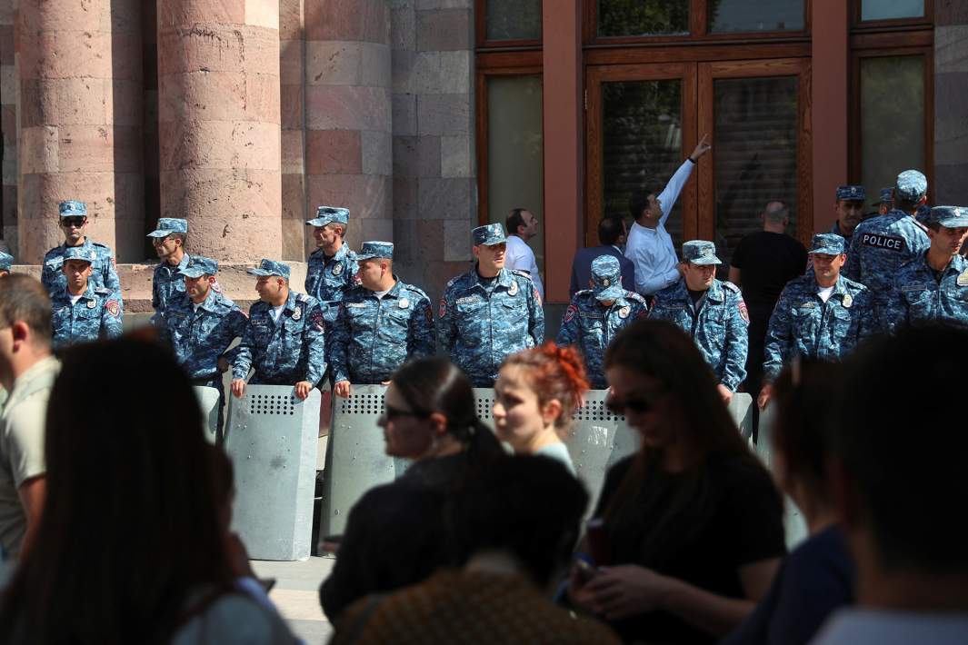 Протестующие собираются перед сотрудниками правоохранительных органов возле здания правительства после начала военной операции азербайджанских сил в регионе Нагорного Карабаха, в Ереване