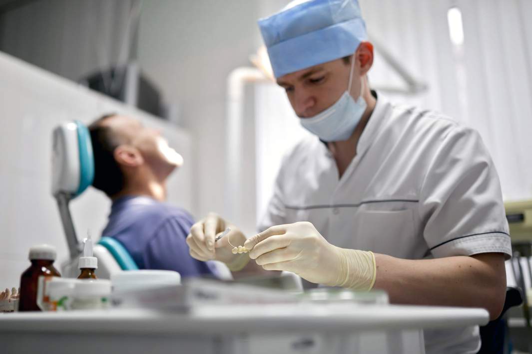 Врач устанавливает металлокерамические коронки пациенту в стоматологической поликлинике
