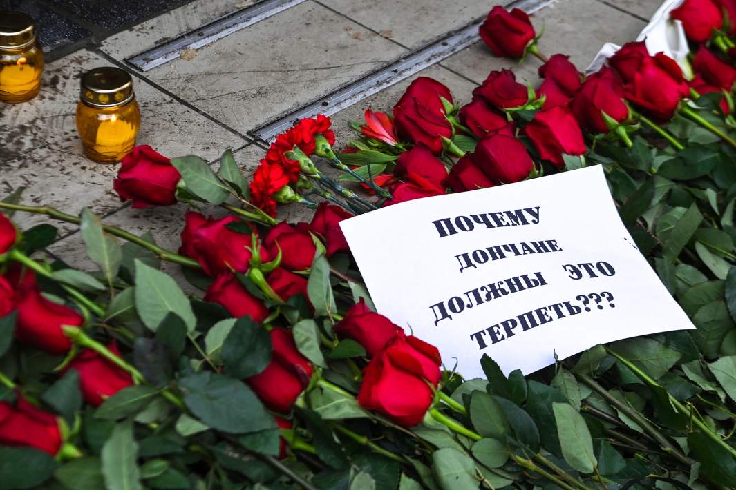 Плакат с надписью «Почему дончане должны то терпеть?» и цветы на месте гибели людей от обстрела в Донецке. 15 марта 2022 года