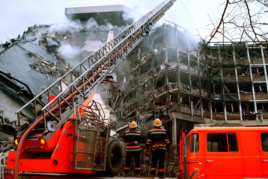 Сотрудники пожарной охраны тушат огонь в разрушенном здании штаба сербской полиции после серии авиаударов. 3 апреля 1999 года