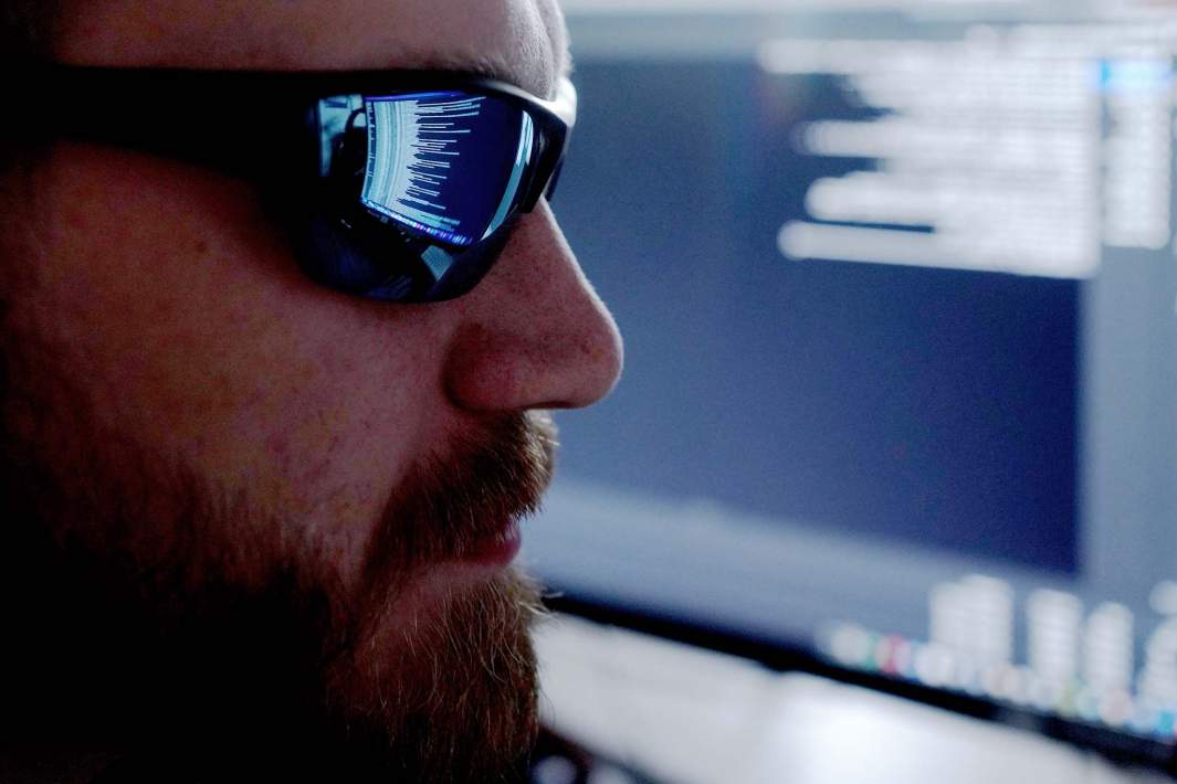 мужчина в очках хакер смотрит в манитор