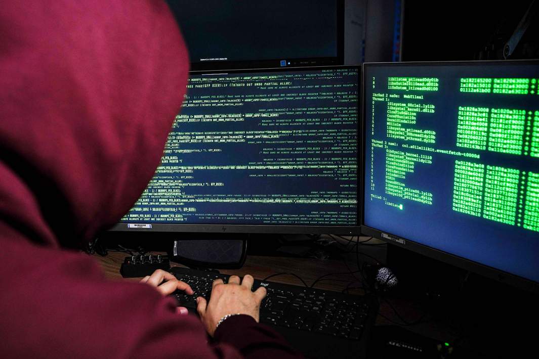 мужчина в красном худи компьютеры с зелеными надписями хакер 