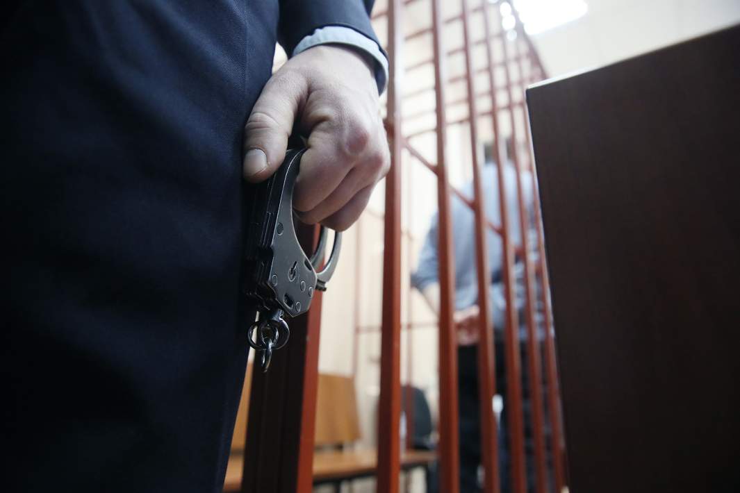 полицейский в суде держит наручники камера 