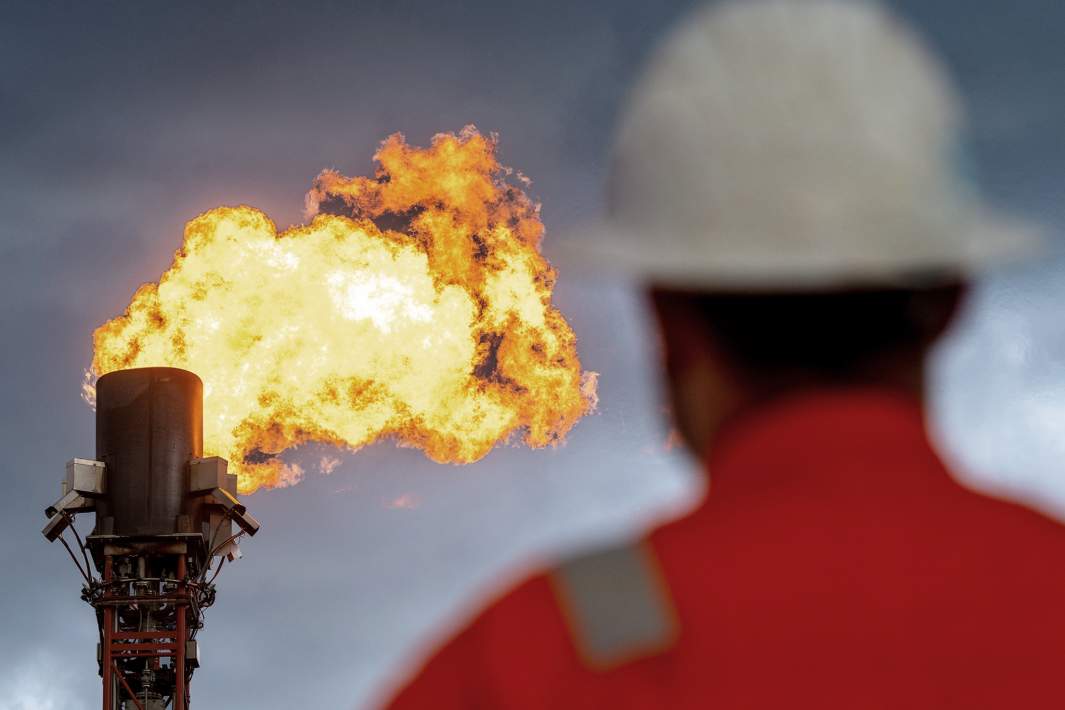 мужчина работник предприятия смотрит на горящий газовый факел