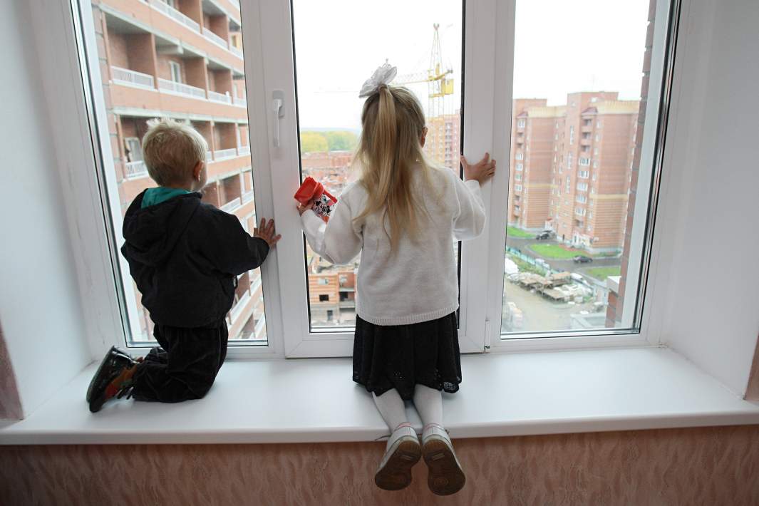 Дети смотрят из окна новой квартиры