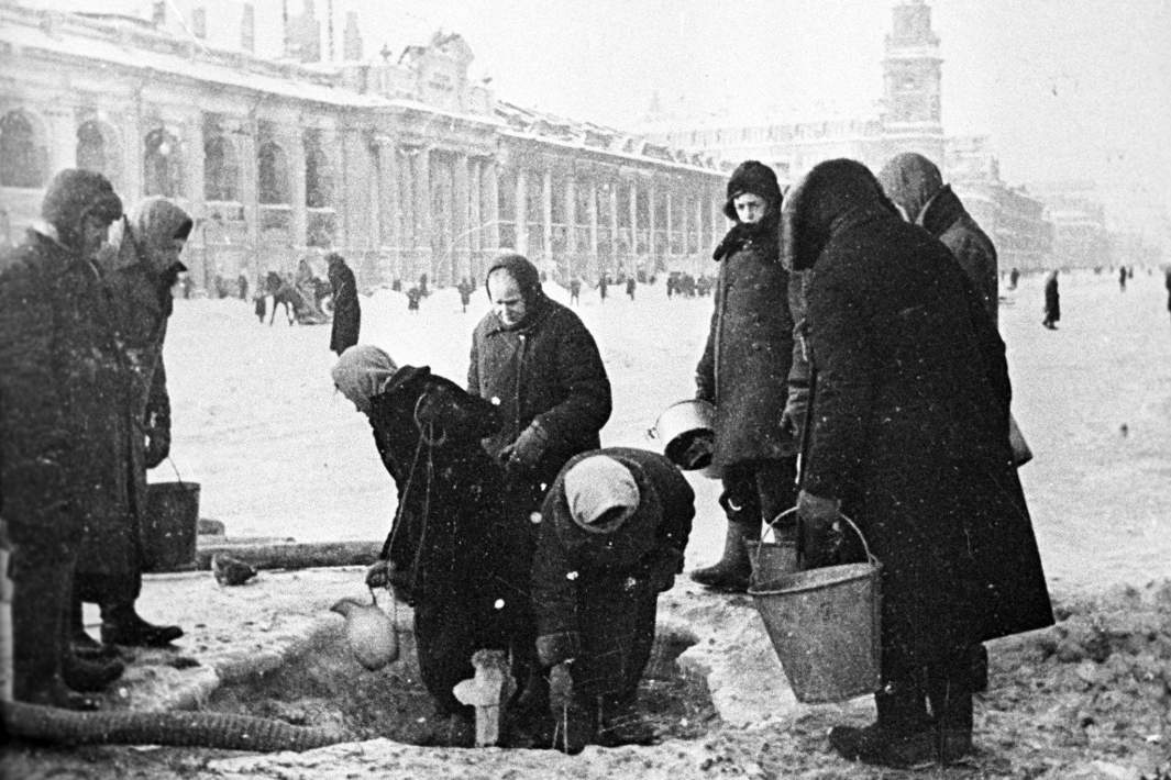 Великая Отечественная война (1941-1945). Жители блокадного Ленинграда набирают воду, появившуюся после артобстрела в пробоинах в асфальте на Невском проспекте. Декабрь 1941 года