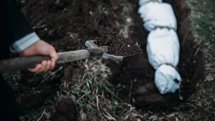 человек закапывает амулет в землю в лесу