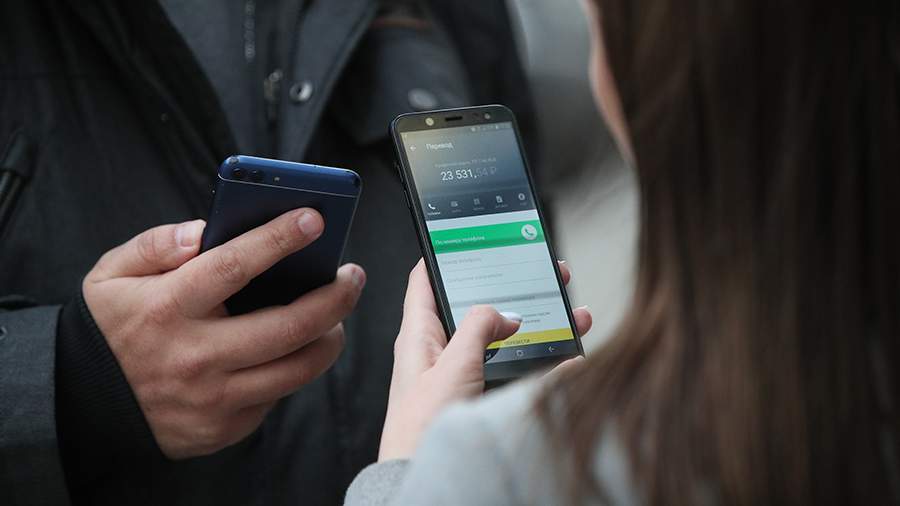 два человека обмениваются деньгами через смартфоны