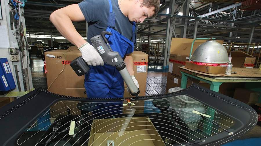 Рабочий подготавливает заднее стекло к установке на автомобиль BMW X3 на конвейере завода «Автотор» в Калининграде