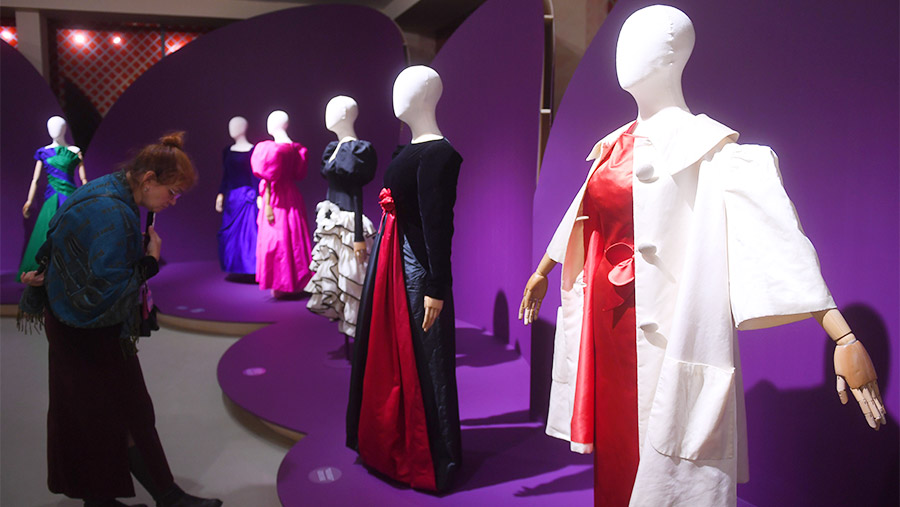 Посетительница разглядывает модели платьев из фонда историка моды Александра Васильева, представленные на выставке «Гламур 80-х»
