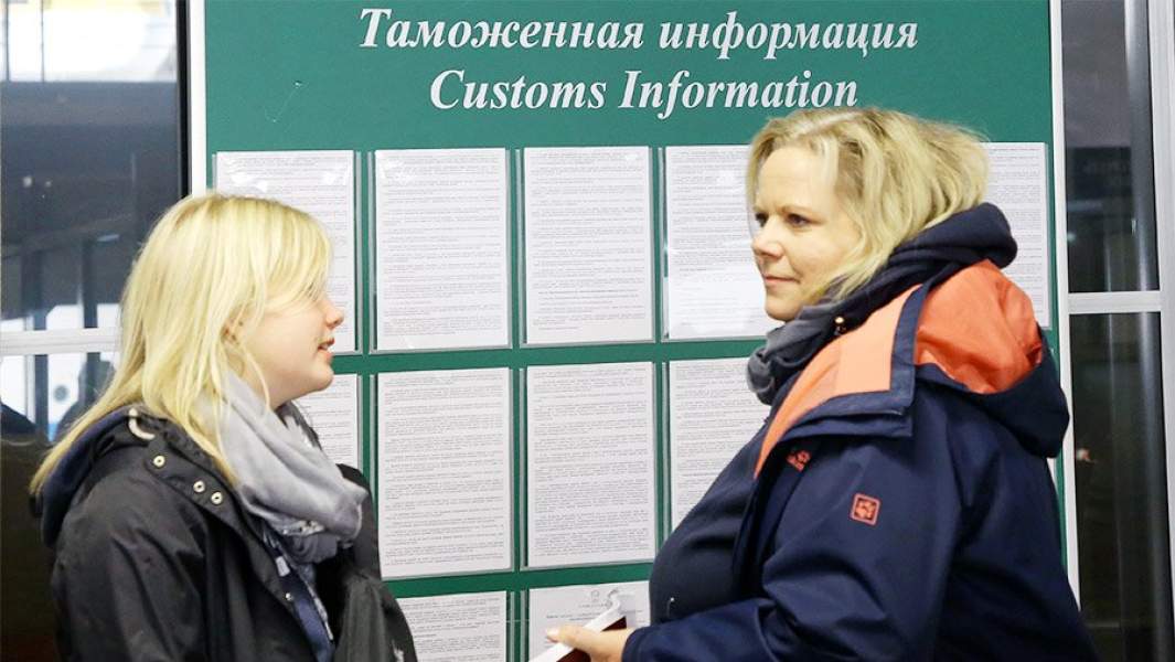 Женщины у стенда с таможенной информацией в  пассажирском порту "Морской фасад" в Санкт-Петербурге
