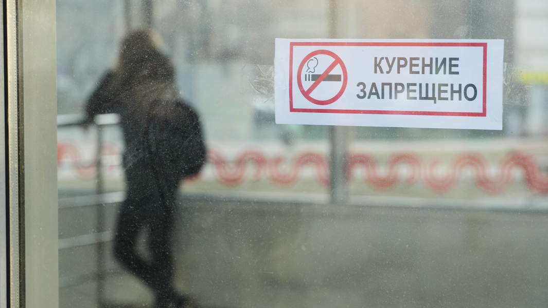 знак "Курение запрещено" и силуэт за стеклом
