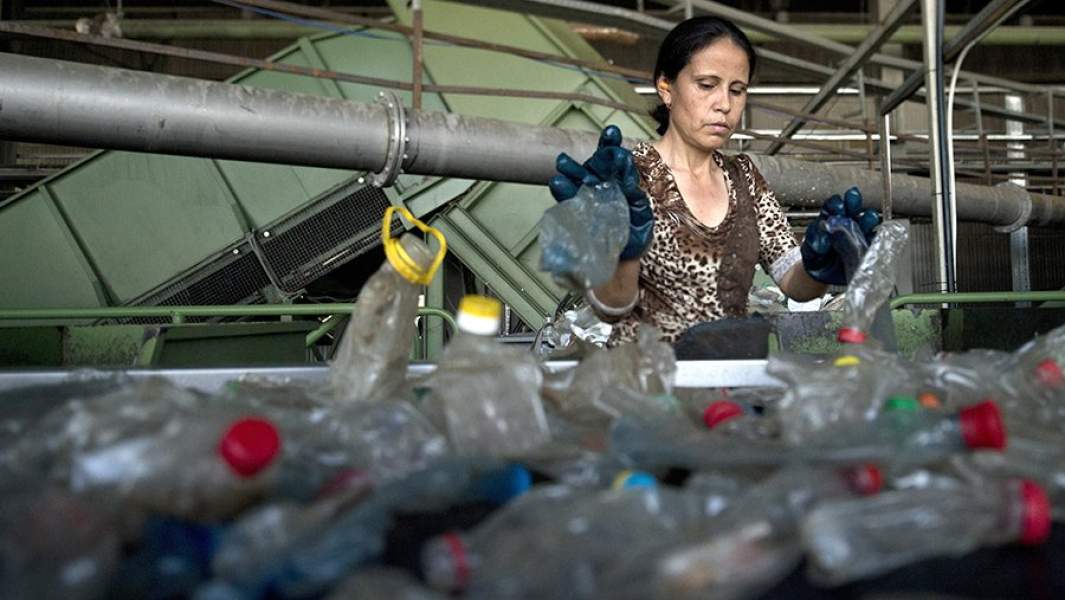 Сотрудница завода сортирует собранные пластиковые бутылки в одном из цехов завода пластмасс