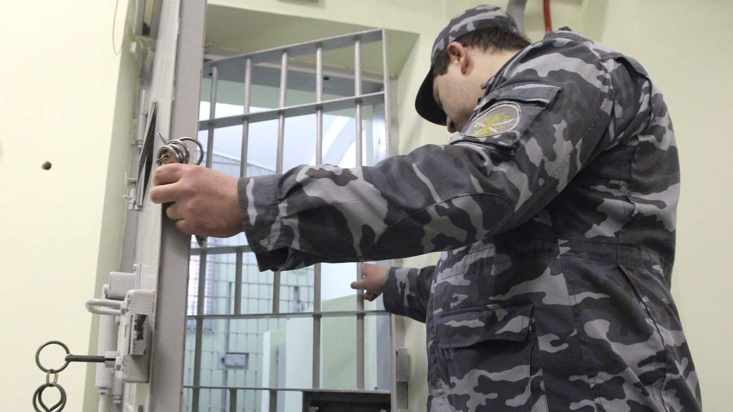 Сотрудник следственного изолятора закрывает дверь карцера