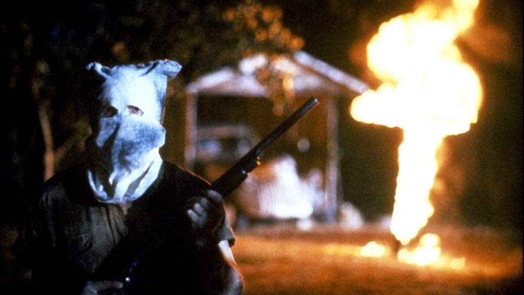 Кадр из фильма «Миссисипи в огне». Куклуксклановец с ружьем на фоне горящего креста