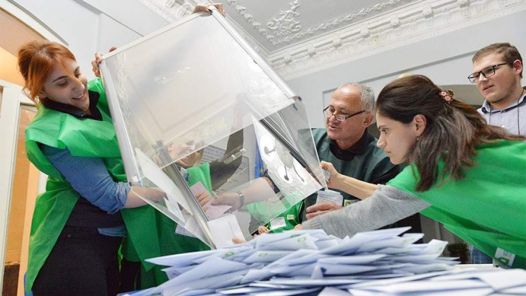 Сотрудница избиркома высыпает избирательные бюллетени из урны для голосования