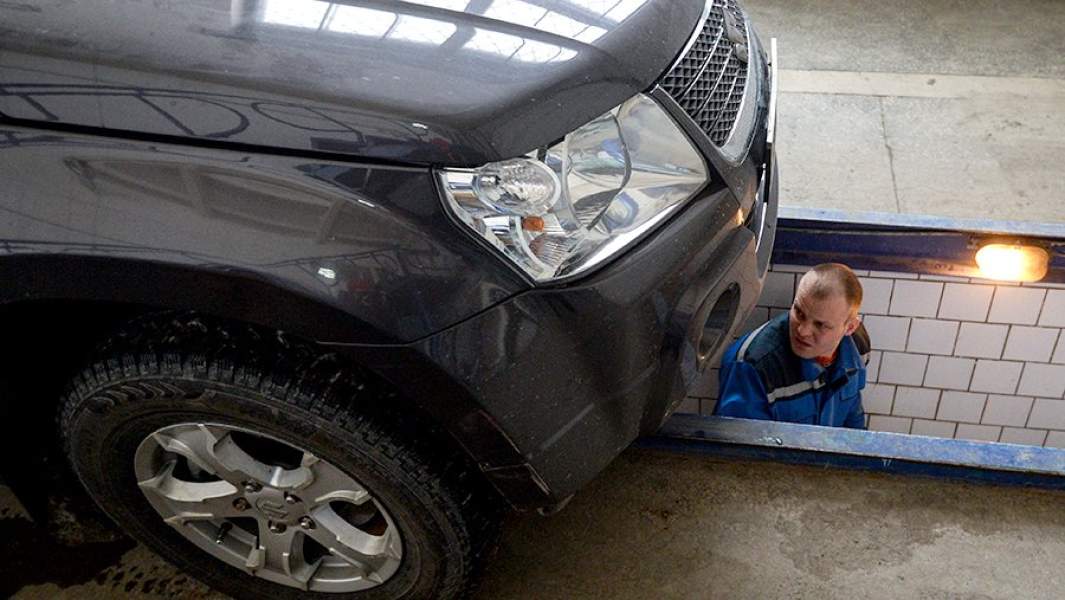 Сотрудник станции  проводит технический осмотр автомобиля