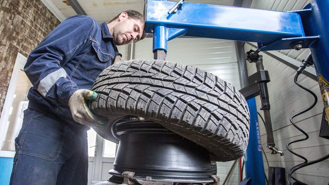 Сотрудник шиномонтажной мастерской во время монтажа шины