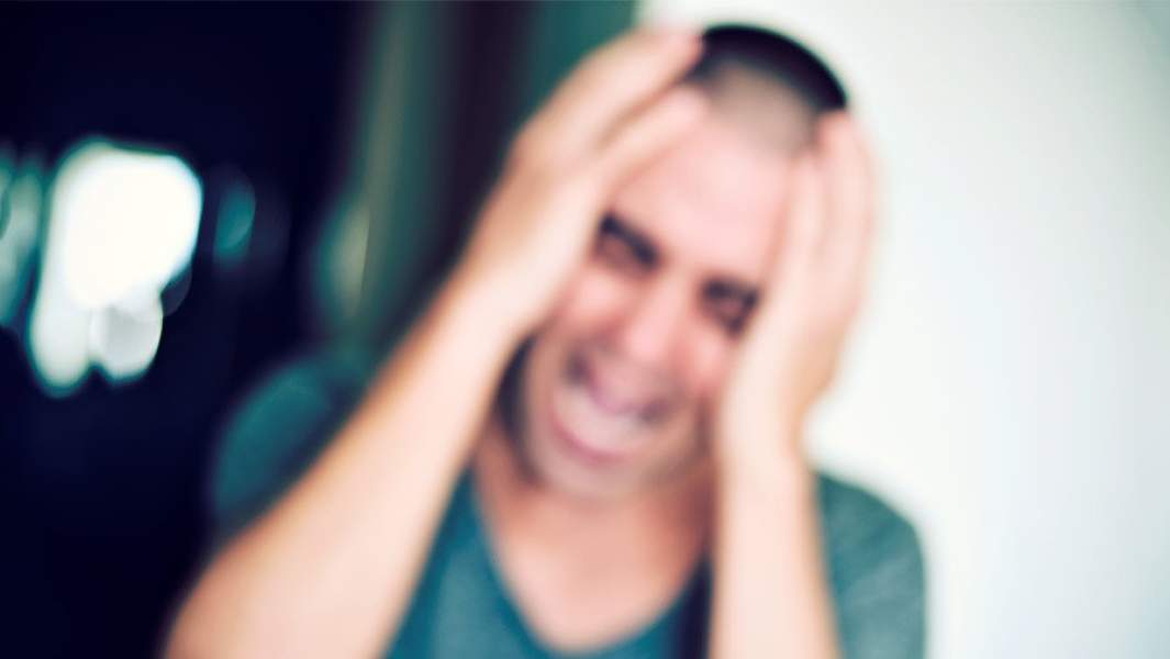 Мужчина держится за голову и кричит, фотография не в фокусе