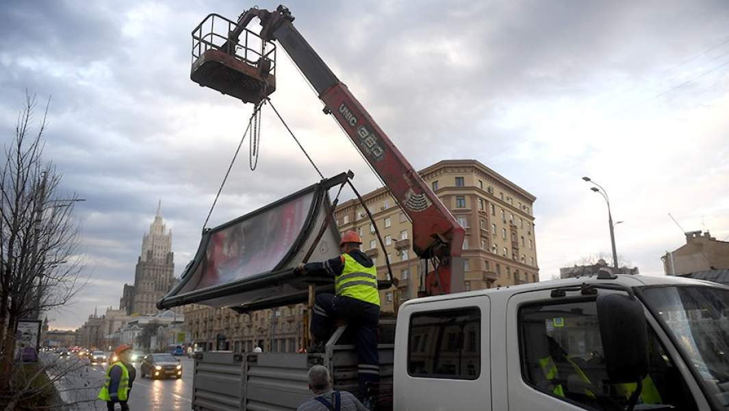 Рабочие грузят рекламный щит на улице Москвы