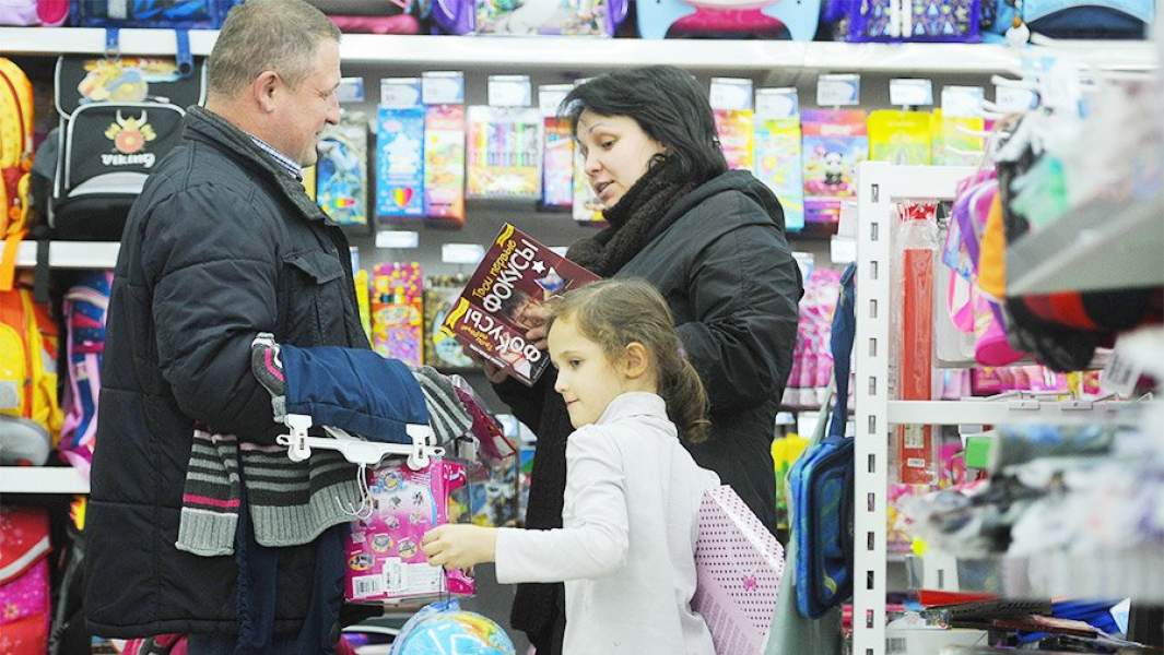 Родители с девочкой выбирают товары для школы