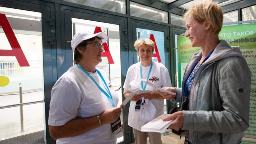 Женщины раздают листовки о ВИЧ перед хоккейным матчем