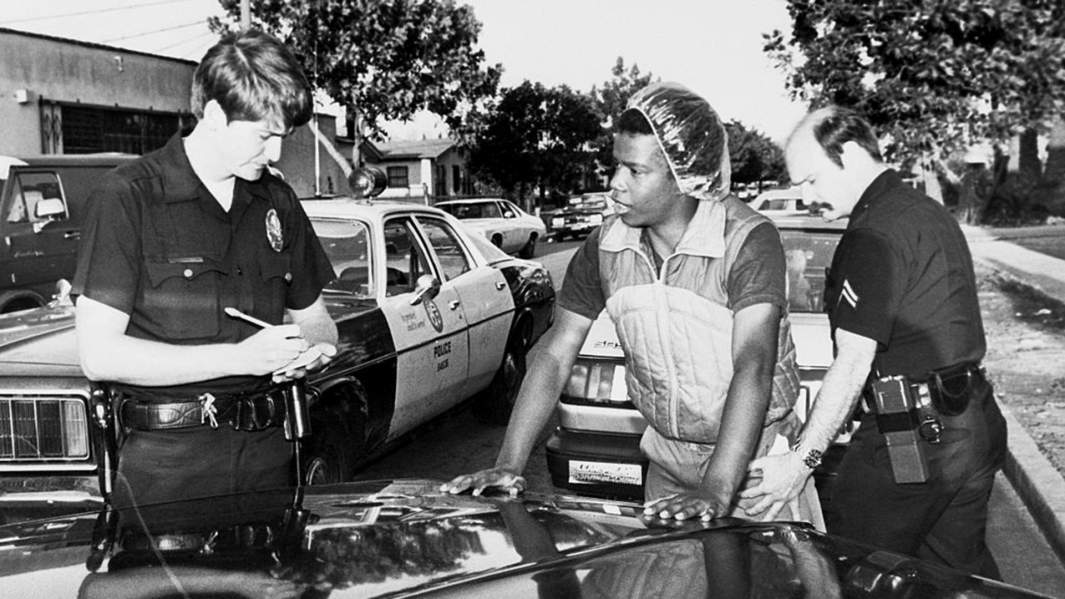 Полицейские досматривают предполагаемого члена банды на предмет оружия и наркотиков, США 1985 год