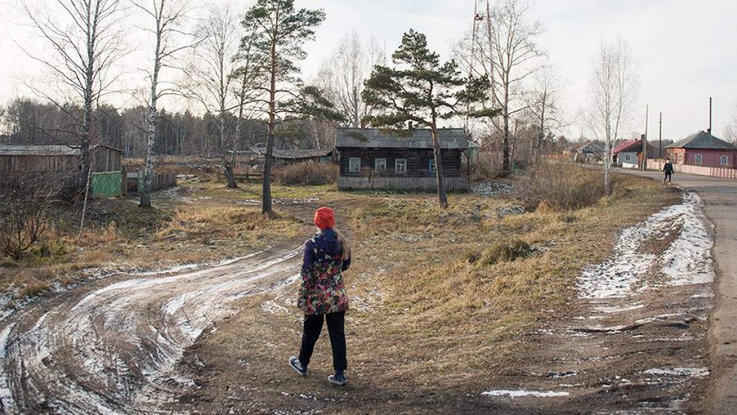 девушка идет по грунтовой дороге, на дальнем плане деревенский дом