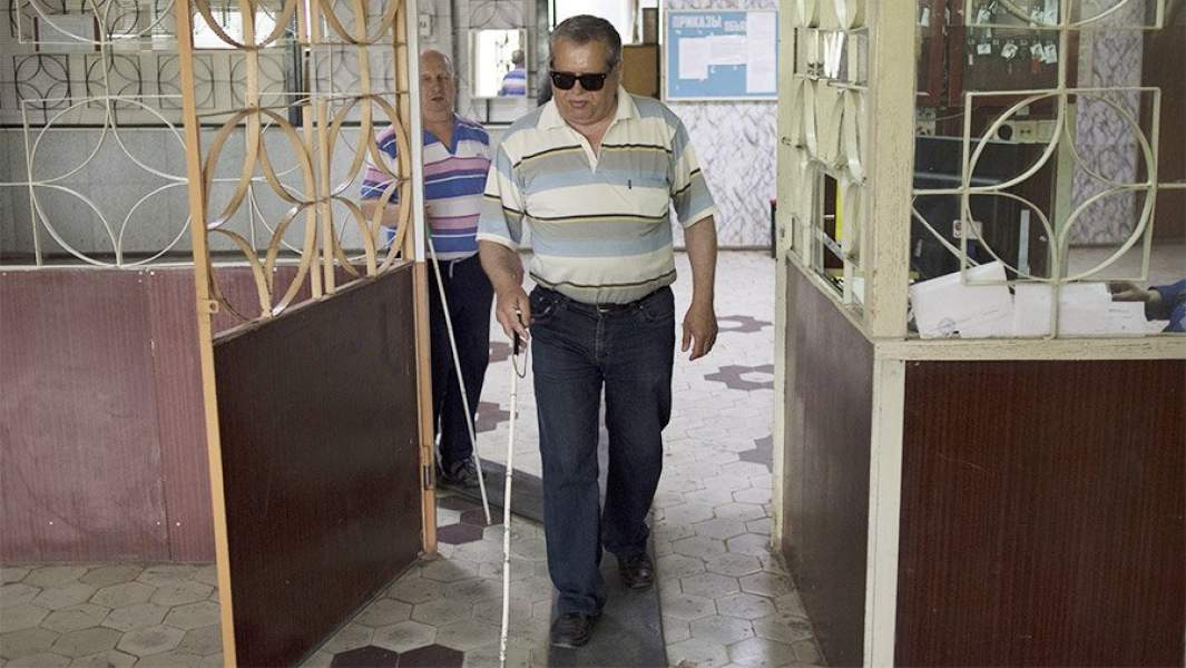 Слепой мужчина с белой тростью на проходной завода