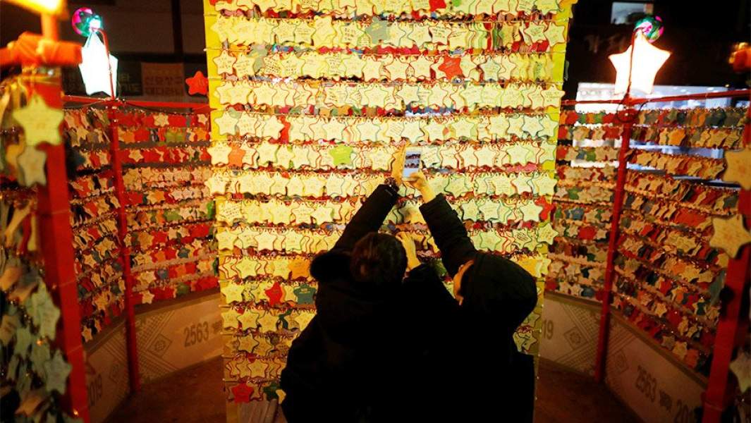 Пара вешает табличку с пожеланием удачи на Новый год в храме в Сеуле