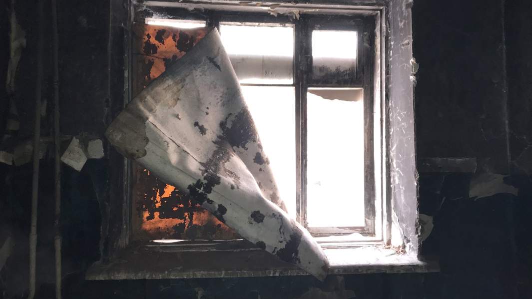 Картонки в оконных проемах этого дома для защиты от бомжей, облюбовавших сгоревшую секцию на первом этаже