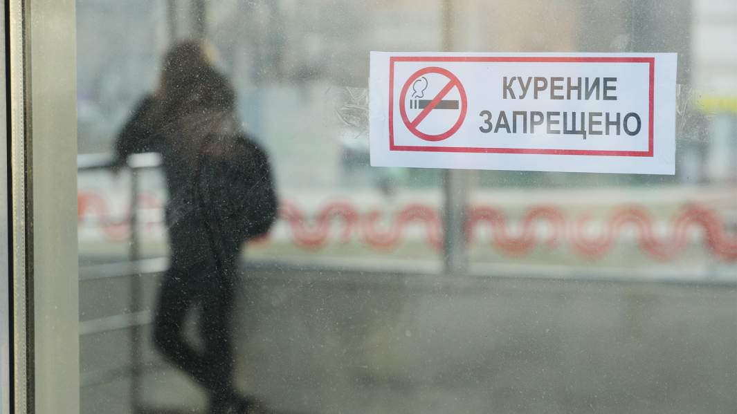 знак "Курение запрещено" и силуэт за стеклом