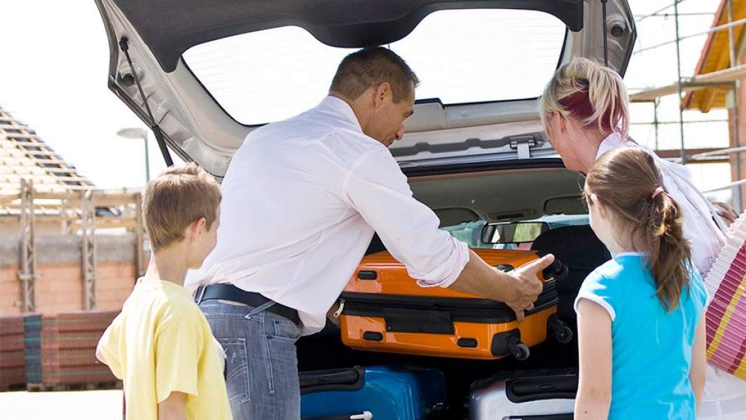 семья пакует чемоданы в машину