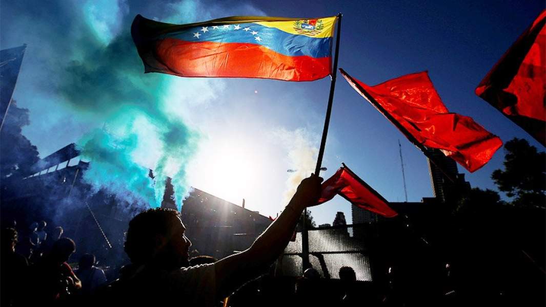 Мужчина развевает венесуэльский флаг возле посольства США в Буэнос-Айресе