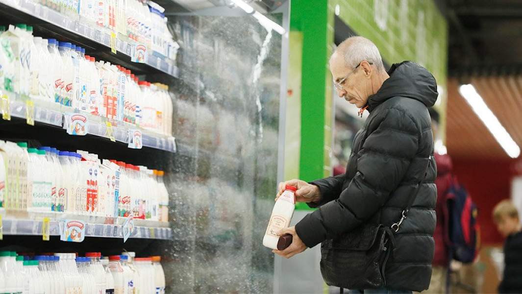 покупатель рассматривает бутылку молока в супермаркете