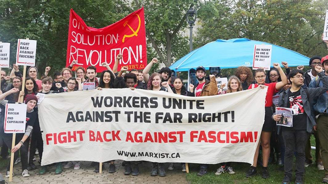 Молодые канадцы несут плакаты против капитализма, расизма и исламофобии