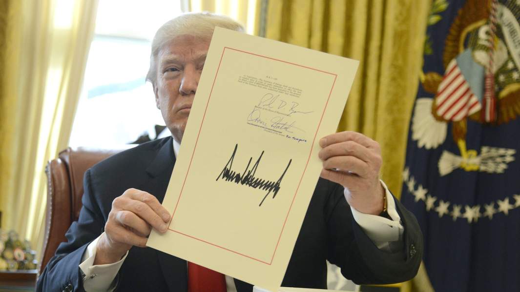 Президент США Дональд Дж. Трамп демонстрирует подписанный законопроект о сокращении налогов на сумму 1,5 трлн долларов