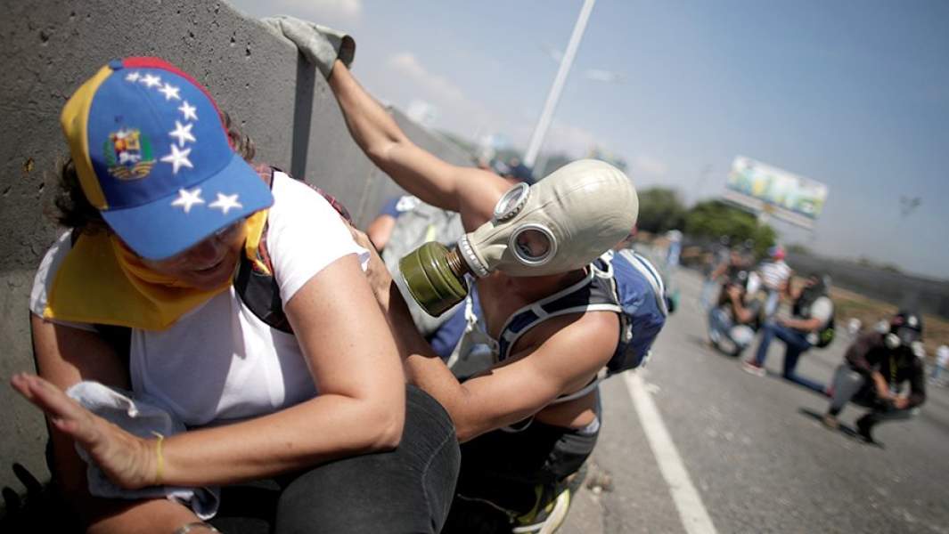 Сторонники оппозиции прячутся от военных армии Венесуэлы рядом с авиабазой Ла Карлота имени генералиссимуса Франсиско де Миранды в Каракасе