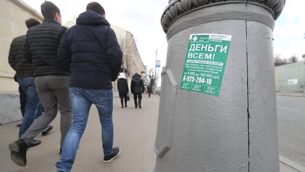 Столб с объявлением о займе и пешеходы