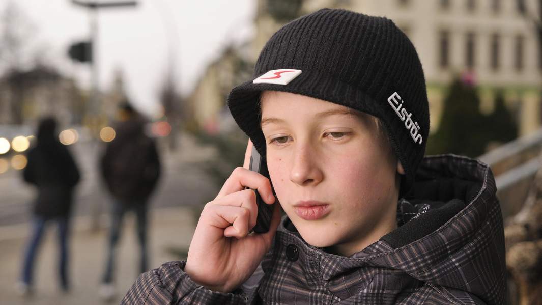 Подросток звонит по мобильному телефону 