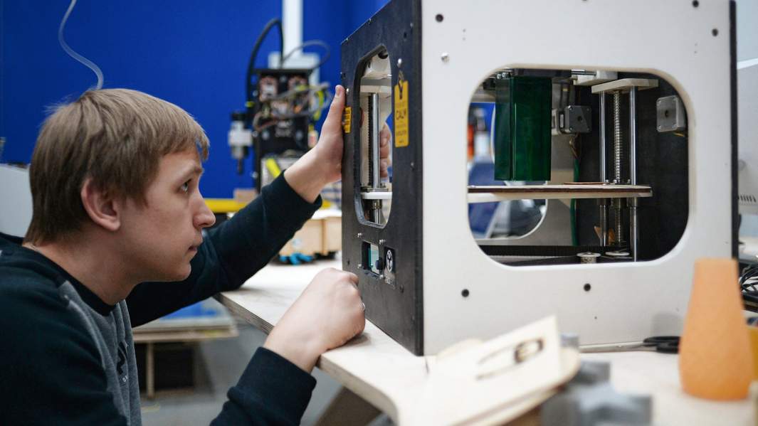 Юноша печатает на 3D принтере