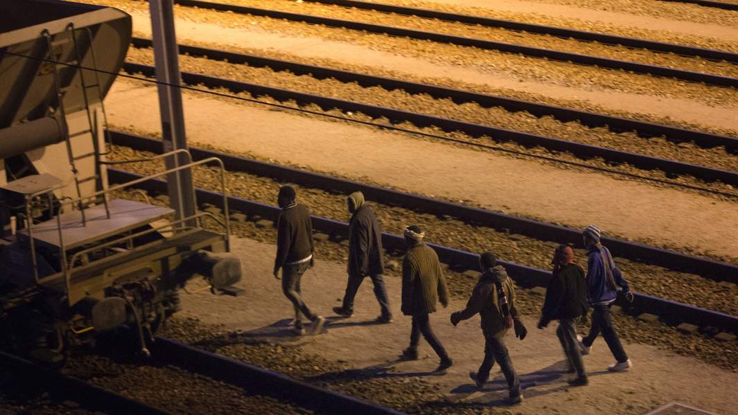 Мигранты идут по железнодорожным путям пытаясь попасть в тоннель 