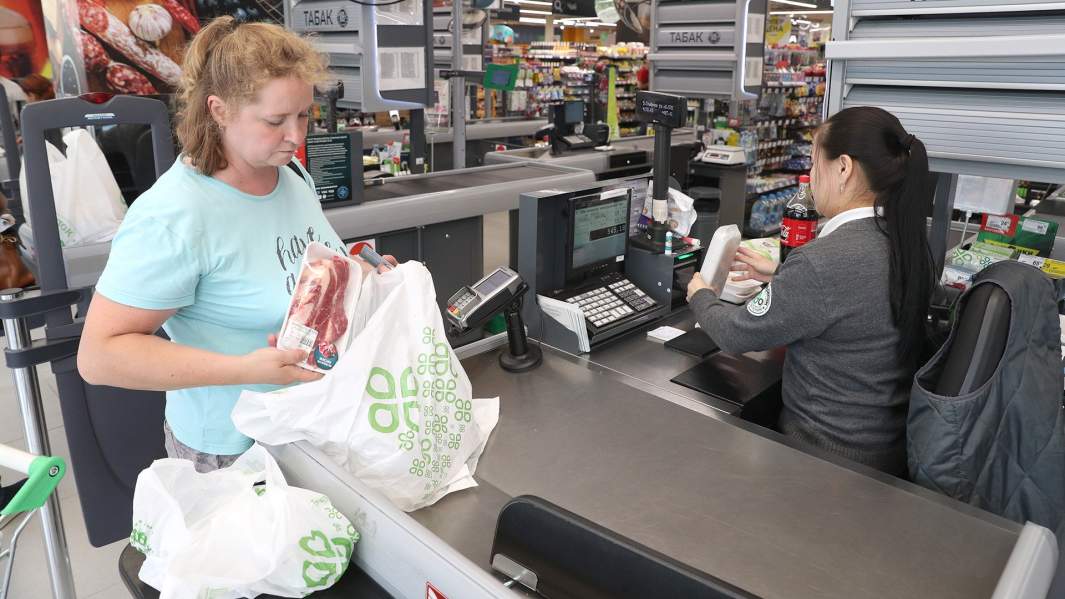 Женщина кассе укладывает покупки в пакеты