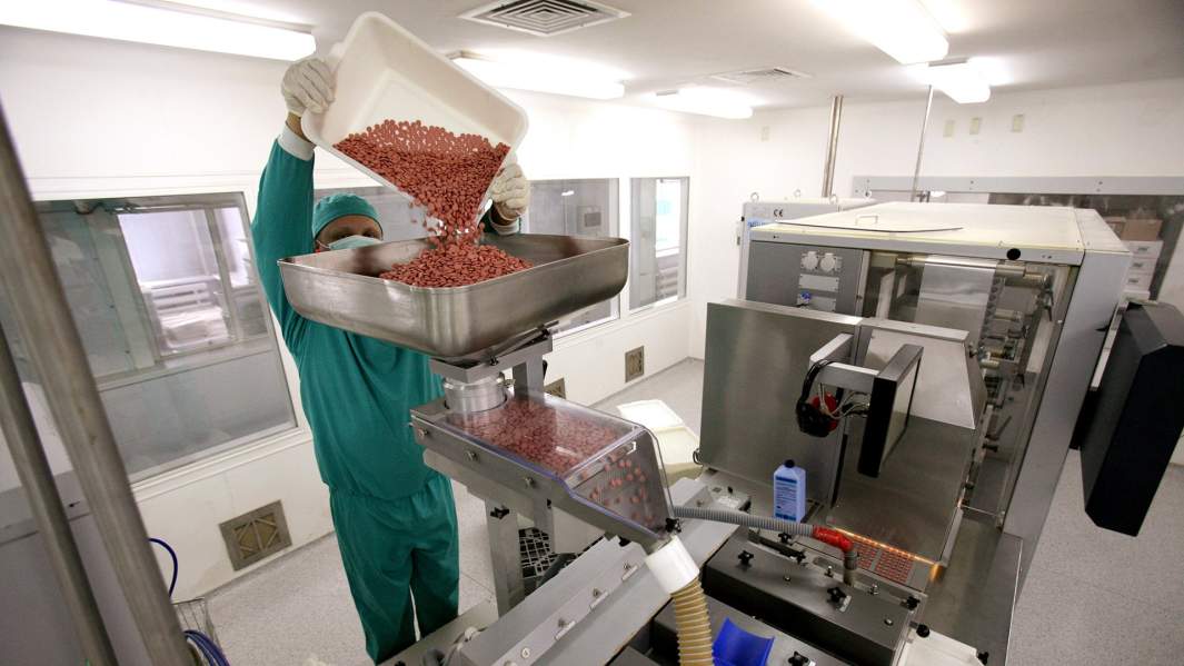 Сотрудник завода фармацевтической компании во время работы на линии упаковки таблетированных препаратов