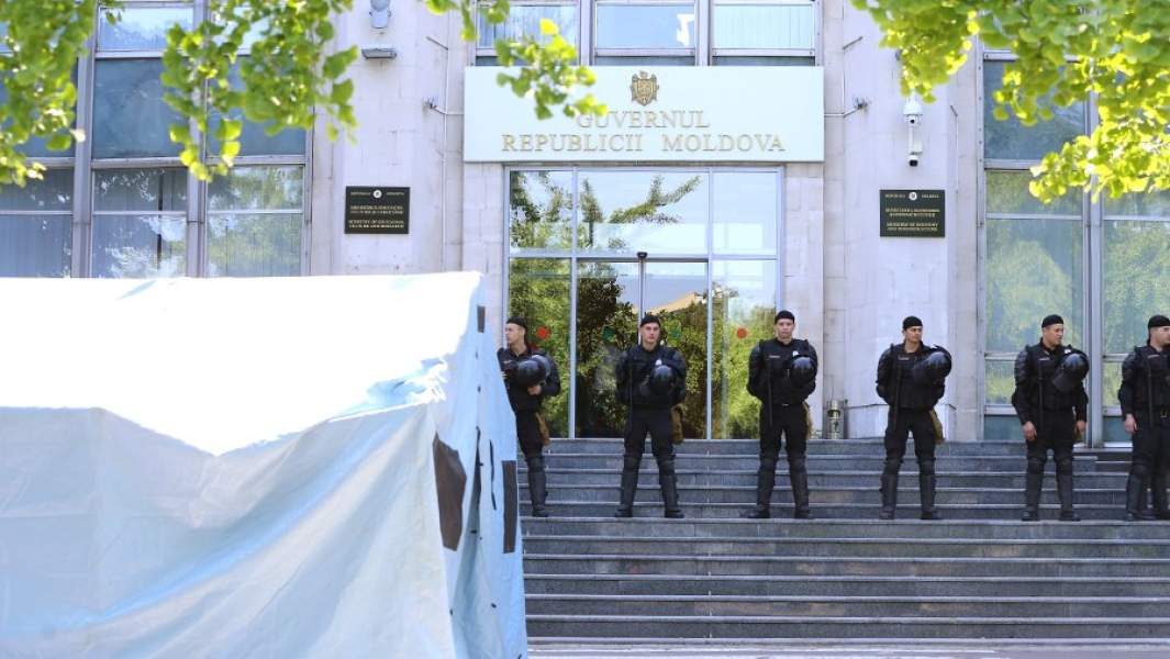 Сотрудники правоохранительных органов охраняют вход в здание правительства Молдавии во время митинга сторонников Демократической партии Молдавии, которые требуют проведения досрочных выборов парламента и отставки президента Игоря Додона
