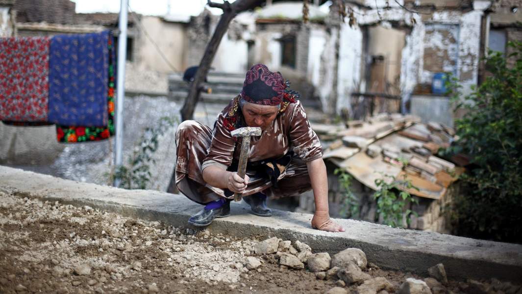 Узбекская женщина ремонтирует жилище, разрушенное в ходе беспорядков в Киргизии
