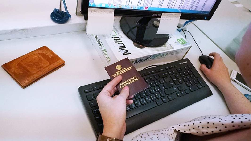 Женщина с пенсионным удостоверением за компьютером