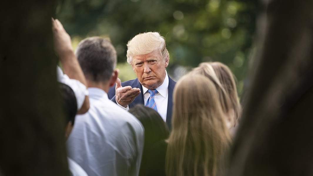 трамп в окружении людей смотрит в камеру